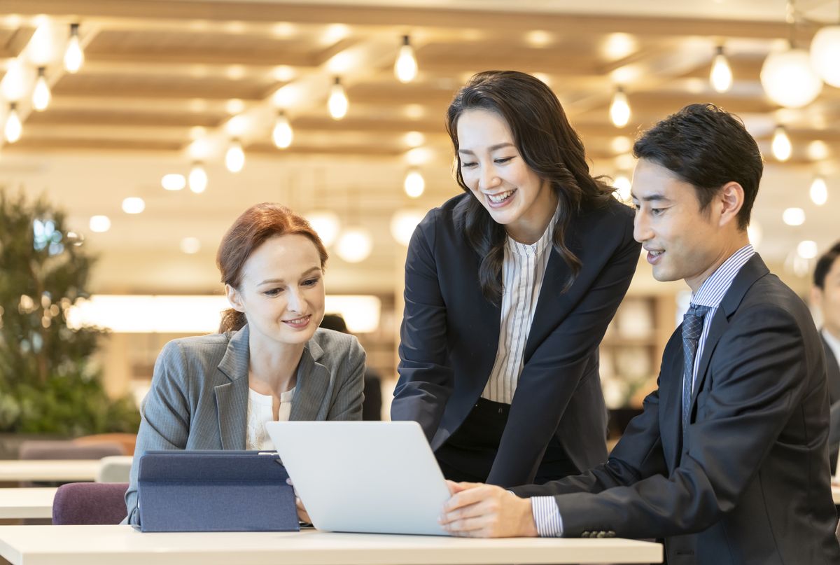 Multinational business team collaborating over a laptop in a Tokyo office